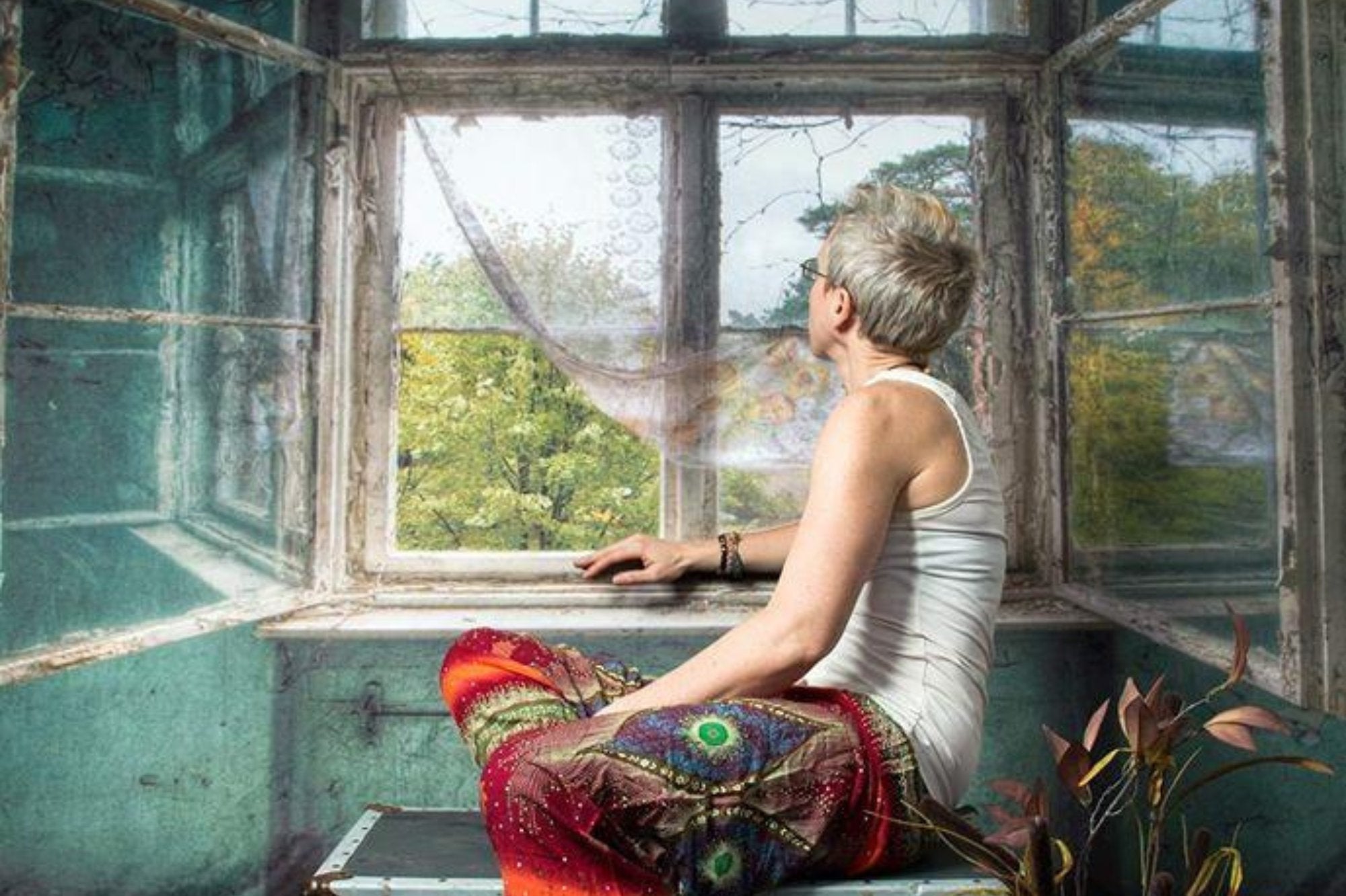 Une femme assise devant un fond de fenêtre à l'intérieur